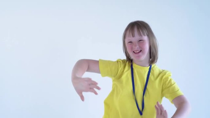 一位身穿黄色t恤的金发少女，胸前戴着奖牌，手里拿着一个运动杯，以取得成就，微笑着。国际唐氏综合症日