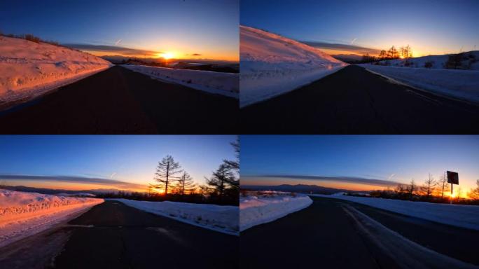 黄昏时在雪山路上驶向日落