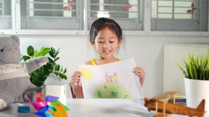 小女孩举起五颜六色的绘画家庭站在纸上牵着地球的手对着相机