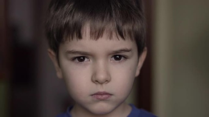 肖像悲伤的小男孩看着相机。思考好奇心的孩子在室内看着相机特写。沮丧的脸眼睛严肃沉思的孩子。严重的学生