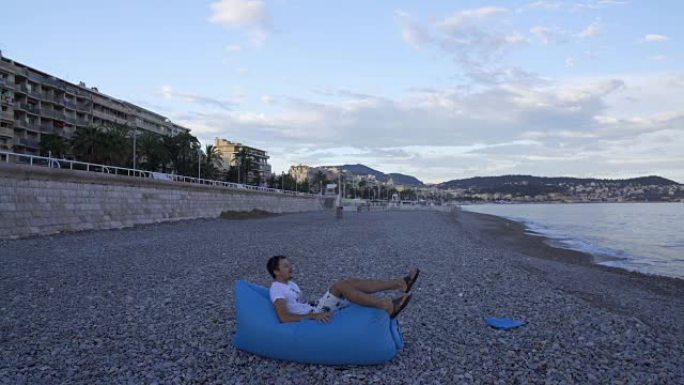 年轻人充气，躺在沙发上享受在海滩上休息
