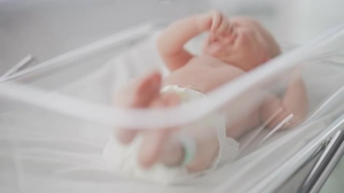 婴儿出生后躺在产科病房摇篮中的婴儿肖像。可爱的新生儿呼唤母亲，哭泣和失眠。分娩和医疗诊所的概念