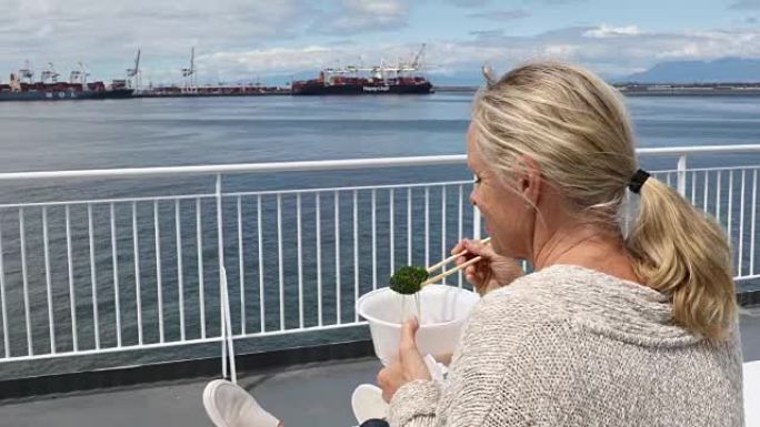 女人在渡船上放松，用筷子吃饭