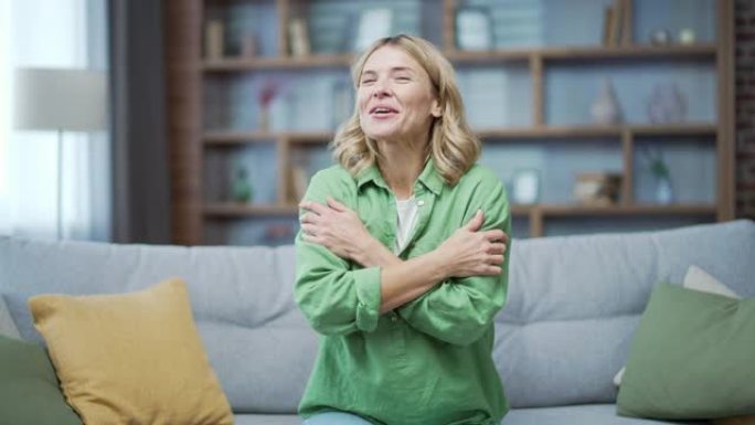 网络摄像头视图。快乐的成熟女人在视频通话中与朋友聊天，坐在家里客厅的沙发上看着相机。