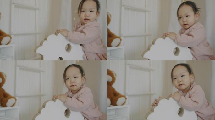 可爱的小女孩在托儿所里玩木马的肖像