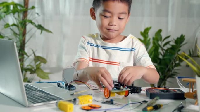 亚洲小男孩拼装板成机器人汽车作业