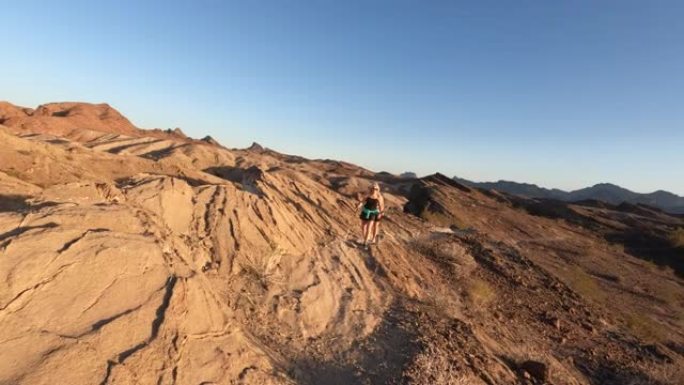 成熟的女性徒步旅行者登上沙漠山脊