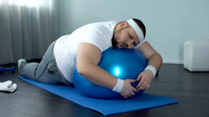 意志薄弱的胖子在健身球上放松，家庭锻炼休息，懒惰