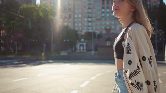 微笑着自信的少女在阳光照耀的右边十字路口四处张望。穿着传统刺绣乌克兰衬衫的黑发正面少年在城市慢动作行