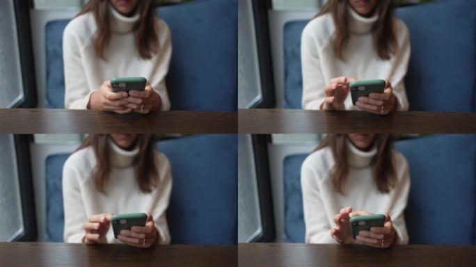 一名妇女坐在餐厅时使用手机的特写镜头