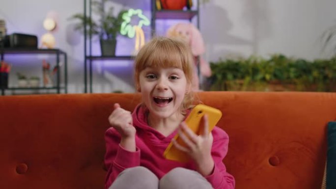 儿童女孩使用智能手机玩，大惊喜，好消息，庆祝网络游戏获胜