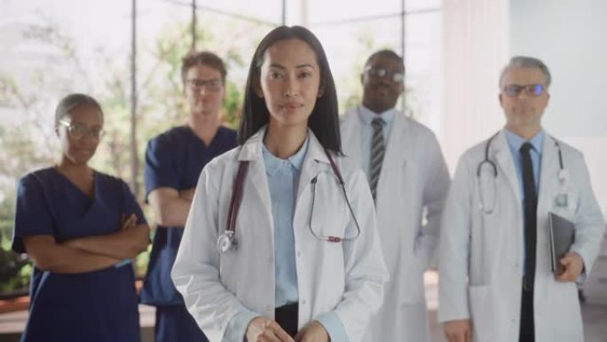 由男女医生，护士和医疗保健专业人员组成的一组快乐的多种族团队为相机摆姿势并微笑。一位自信的亚洲医生的