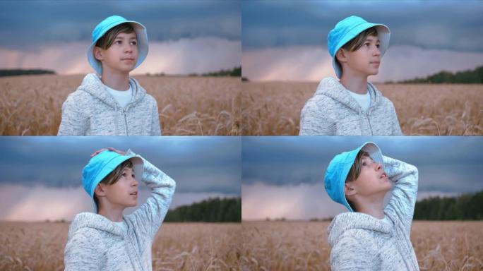 雷雨开始时，戴着帽子的有趣男孩站在田野里，看着多雨的天空，电影般的steadicam拍摄