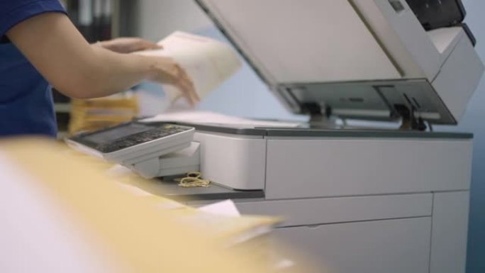通过使用多功能复印机复印文件来处理文件的女性工人。