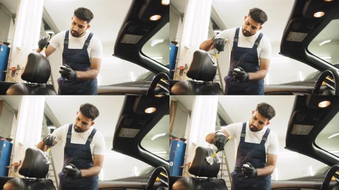 年轻英俊的集中大胡子男人使用清洁刷和清除汽车空调通风格栅上的灰尘。汽车细节和代客概念。汽车细节和代客