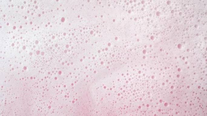 水浪流在粉红色背景上产生大量泡沫