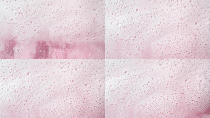 水浪流在粉红色背景上产生大量泡沫