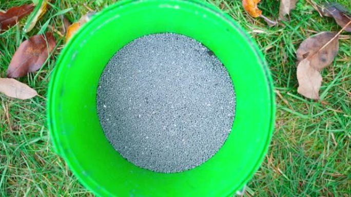 桶中的灰色颗粒土壤肥料特写。过磷酸钙用于在秋天喂养树木的土壤