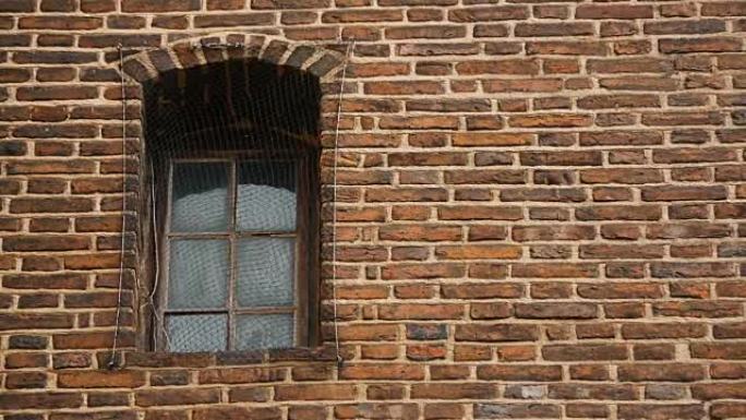 窗户覆盖着金属网，中世纪监狱的古砖墙，被囚禁