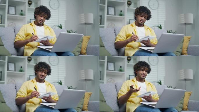 年轻英俊的印度男学生在线学习远程坐在家里的沙发上拉丁人自由职业者看视频