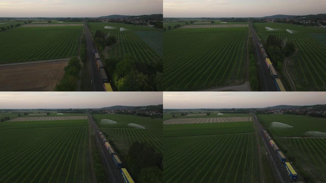 空中无人机拍摄了从上方穿过农田的货运列车