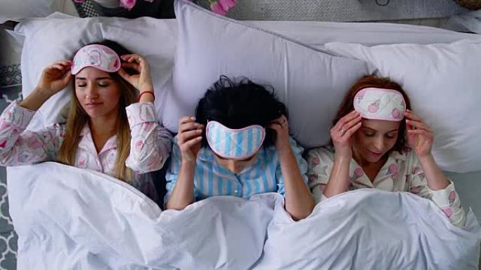 俯视图，三个漂亮的女孩在床上睡觉，并戴上眼圈绷带睡觉