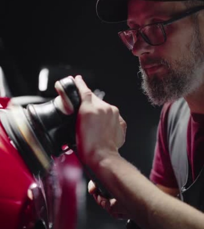 垂直屏幕: 成年男子在细节工作室工作，将抛光膏撒在红色跑车上，使其恢复出厂状态。技术员用抛光机抛光挡