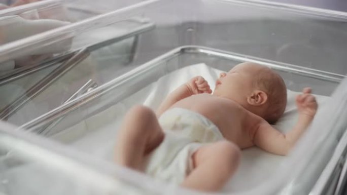 可爱的情感新生婴儿躺在医院的婴儿床。有趣的打哈欠的高加索婴儿花时间在产科诊所，准备睡觉。医疗保健、怀