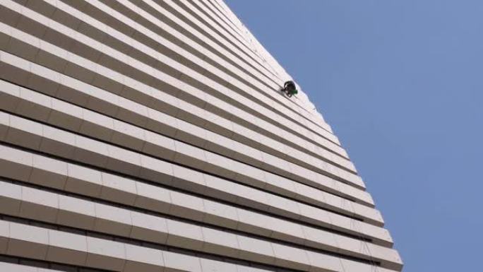 一名清洁公司的工人在蓝天下在高海拔的摩天大楼上工作。
