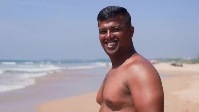 沙滩上白白露齿微笑的快乐亚洲男人的肖像。
