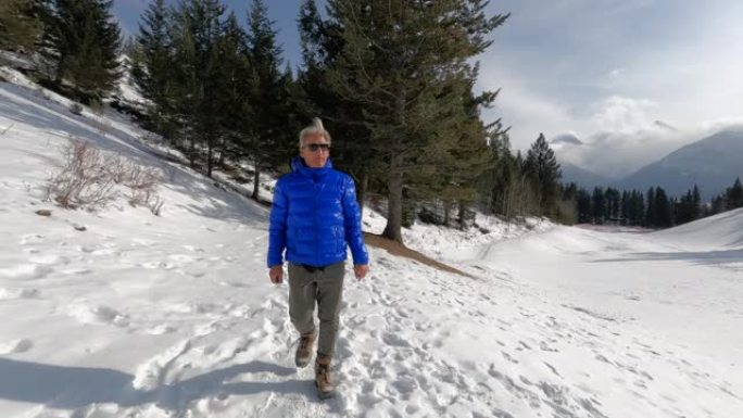 成熟的人沿着山路在雪中徒步旅行