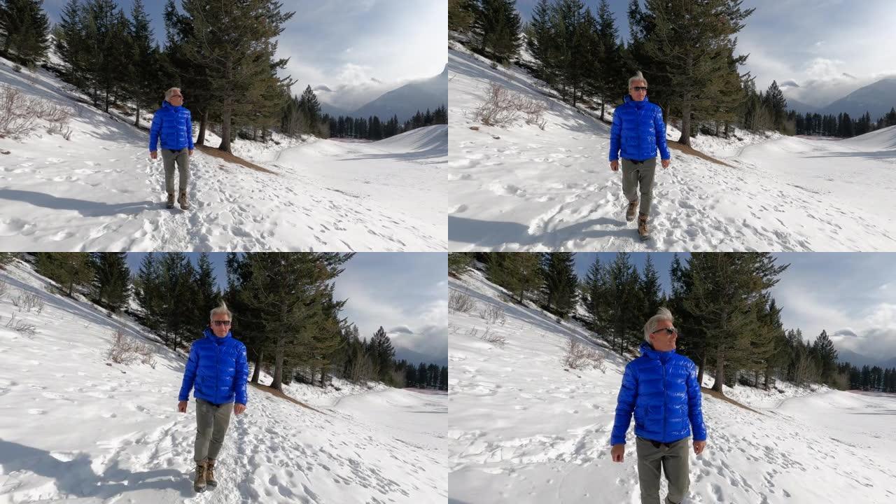 成熟的人沿着山路在雪中徒步旅行