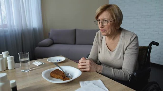 沮丧的高级妇女在养老院感到孤独，拒绝吃饭，年老