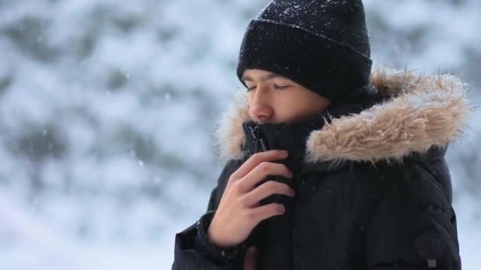 肖像画年轻的冰冷男孩在寒冷的天气中站在森林地区