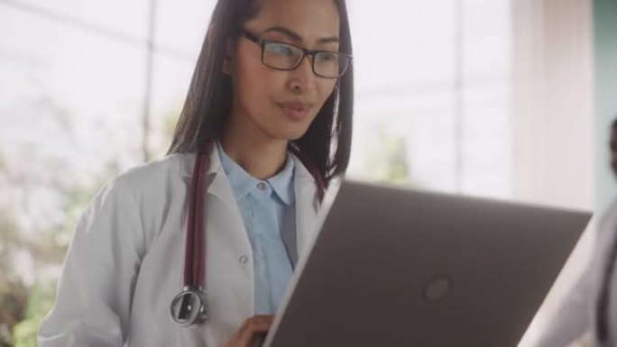 医院办公室使用笔记本电脑的医疗保健专业人员的肖像。穿着白大褂的亚洲诊所医生在线指定处方，更新电子健康