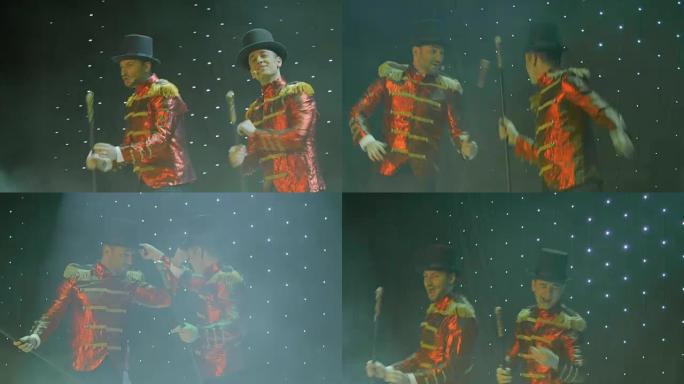 两个穿着红色尾大衣的时尚男人在剧院的舞台上跳舞和唱歌