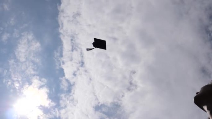 刚毕业的大学女学生将帽子慢动作扔向天空