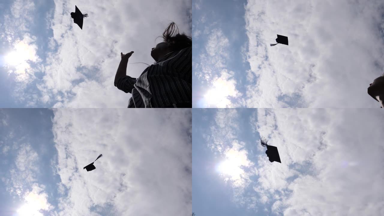 刚毕业的大学女学生将帽子慢动作扔向天空