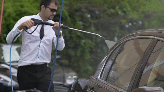 富裕的家庭司机用水喷洒汽车，清洁昂贵的车队