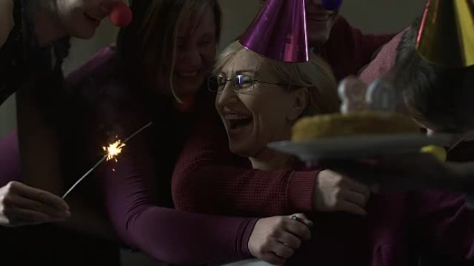 朋友和家人在80岁生日聚会上拥抱幸福的女人，庆祝