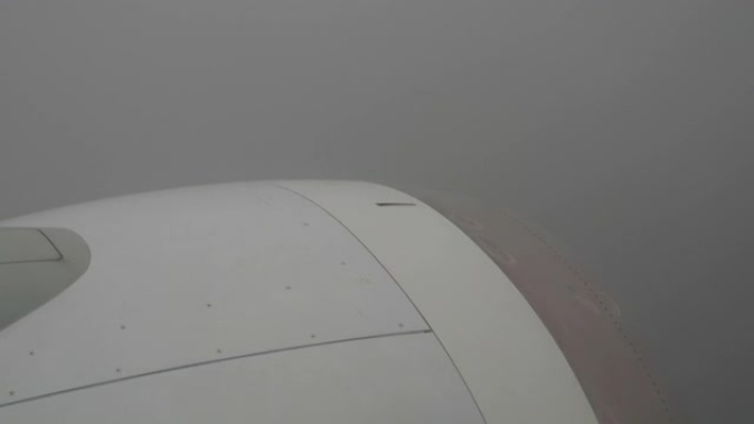 从飞机上看浓密的灰色云层，看不到天空。恶劣天气下的湍流。透过云层你可以看到森林和房屋。在带有叶片的框