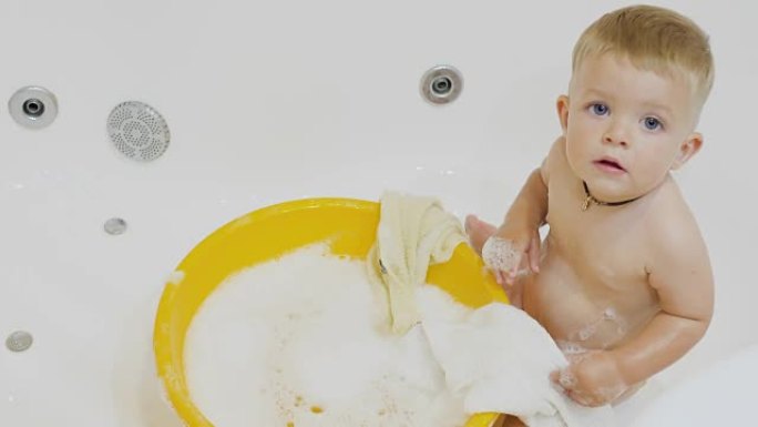 可爱的小男孩在浴缸里玩毛巾