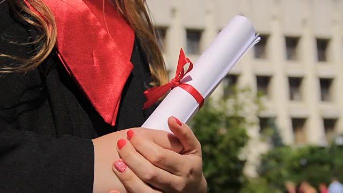 女人穿着毕业礼服拿着文凭，展望幸福的未来