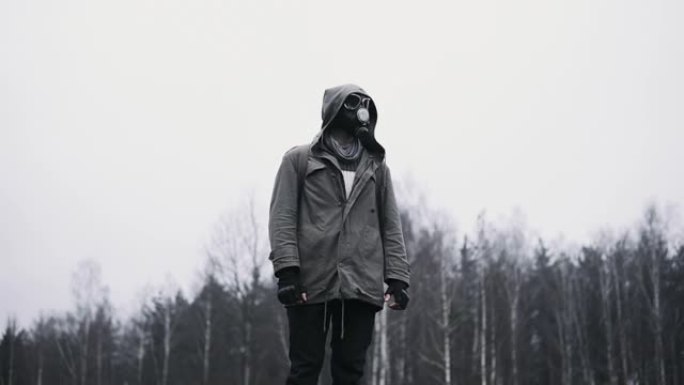 戴着防毒面具的蒙面男子站在黑暗的森林里。跟踪者概念，核或化学灾难后的男性幸存者