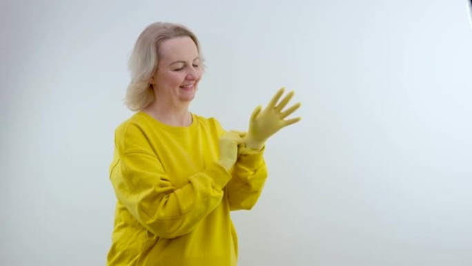 家庭主妇戴上乳胶黄色手套家用手套和蓝色背景上的白色三聚氰胺海绵。用于清洁各种表面的污垢和污渍的通用工