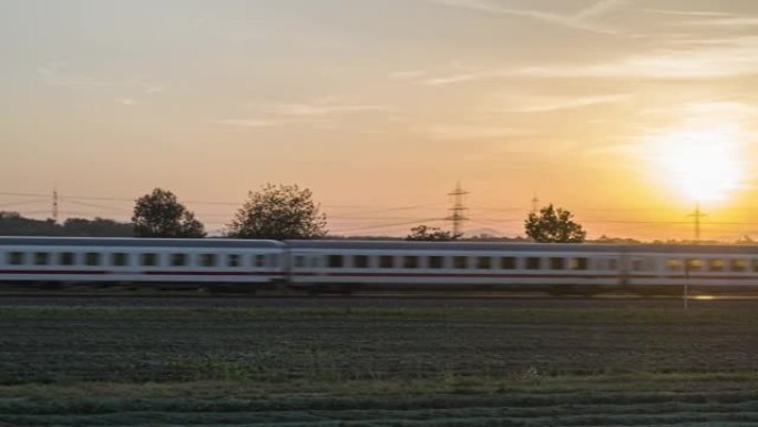 空中无人机拍摄了一列货运火车在日落时分穿过农田