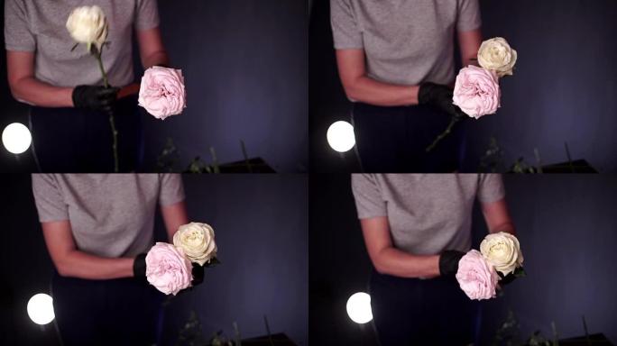 花店收集了一束牡丹，白色和粉红色的玫瑰。花匠戴着黑色防护手套的手的特写镜头。花店创造了一束美丽的花束