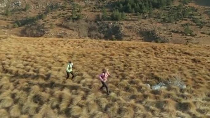 空中两名女选手在清晨的阳光下在草木山顶上奔跑