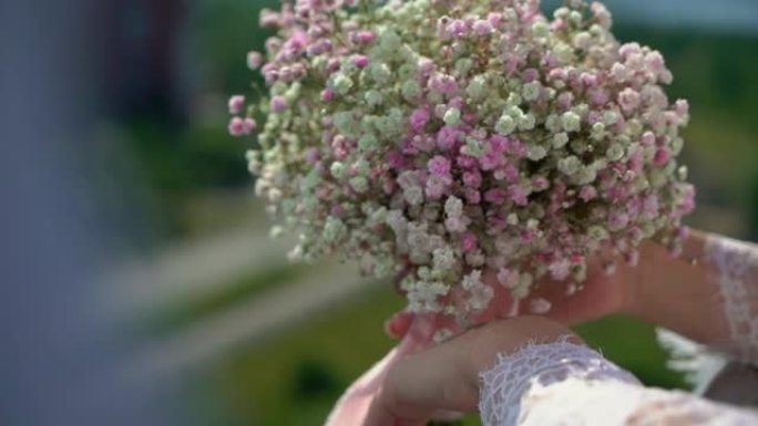 女人拿着一束白色和粉红色的小灌木花。婚礼当天的新娘。