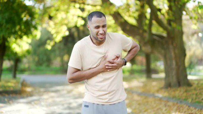 一个年轻人在公园晨跑时心脏病发作或胸痛。他痛苦地抓住胸口，喘着粗气。